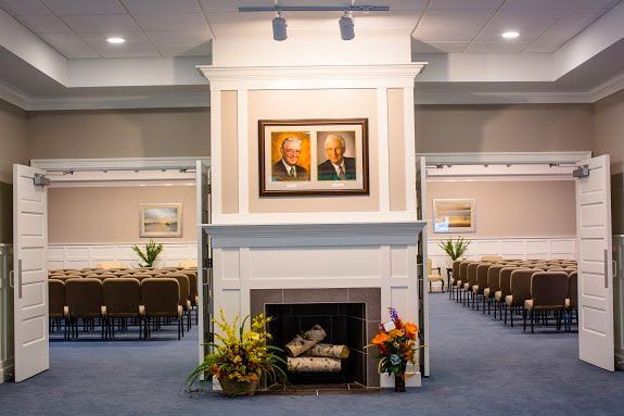 a funeral home with a fireplace and two portraits on the wall .