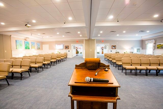 a large room with rows of chairs and a podium with a microphone on it .