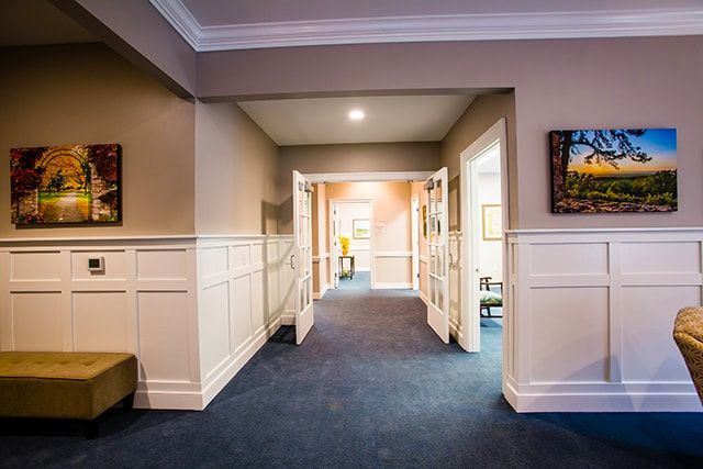 a hallway in a house with a blue carpet and two paintings on the wall .