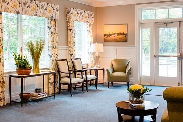 a living room with two chairs , a table , and a painting on the wall .
