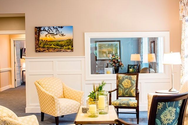 a living room with chairs , a table and a painting on the wall .