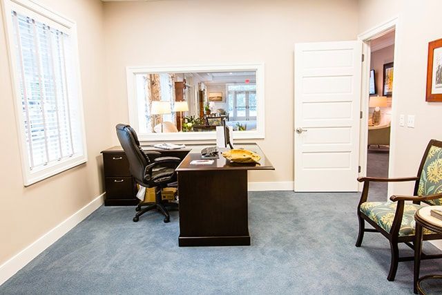 a room with a desk , chair , table and window .