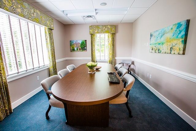 a conference room with a long table and chairs and a painting on the wall .