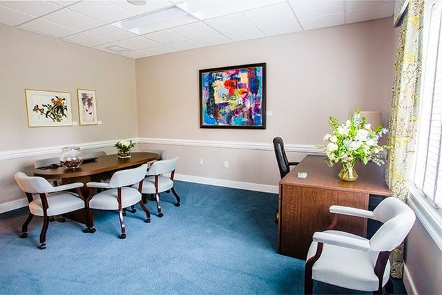 a conference room with a table and chairs and a painting on the wall .
