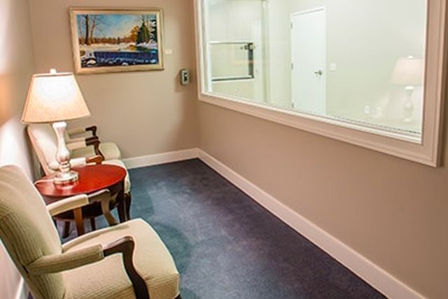 a room with chairs , a table , a lamp and a large window .