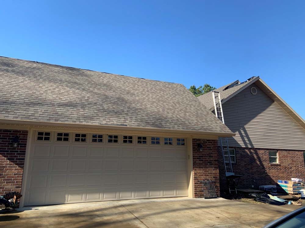 A brick house with a large garage door and a car parked in front of it.