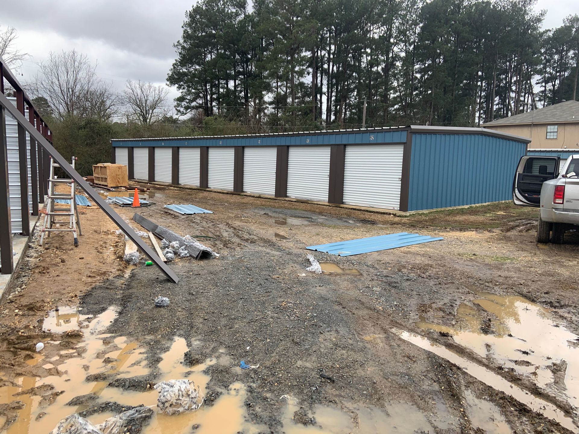 A row of garages are being built in a muddy area.