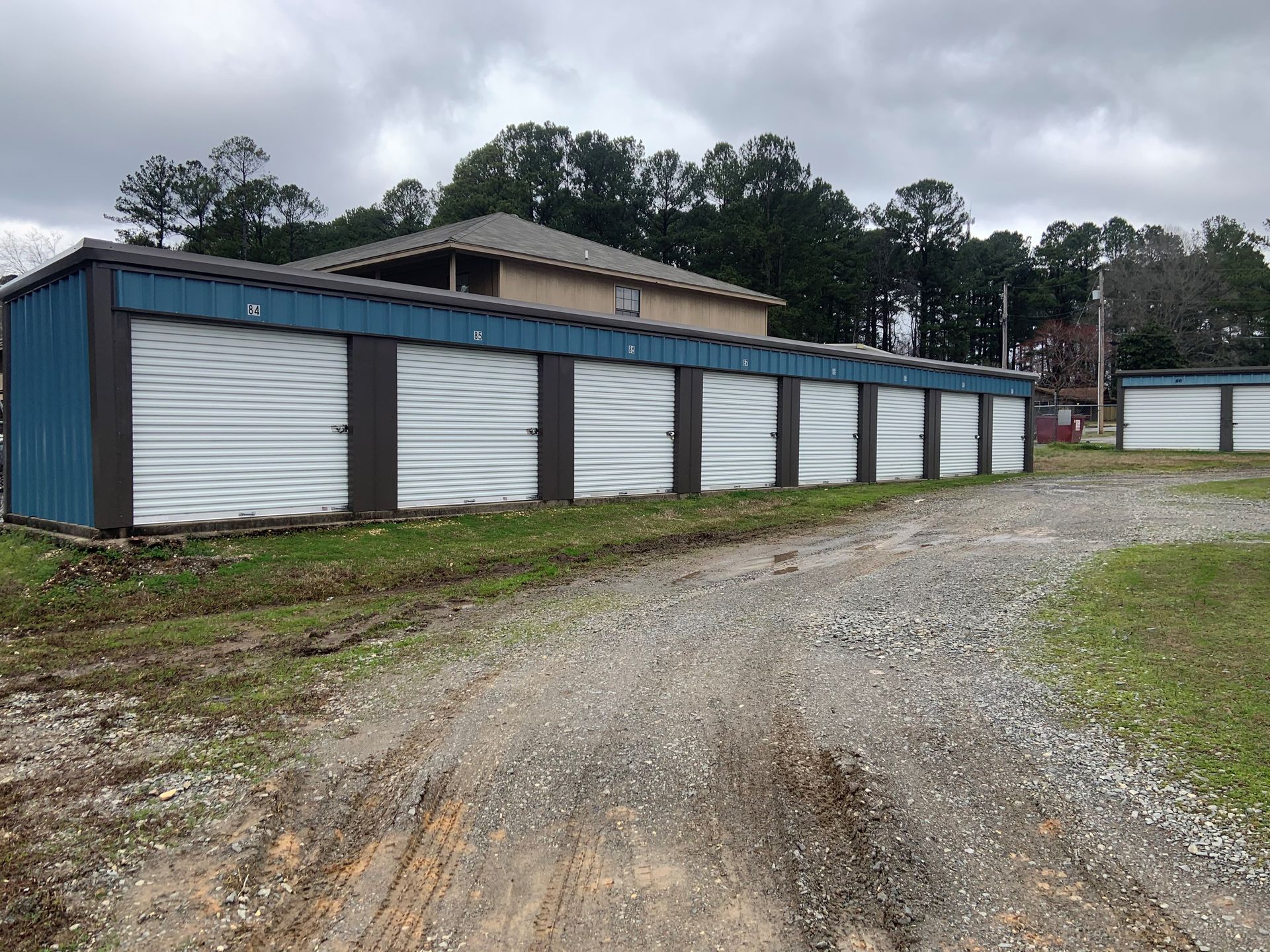 A row of storage units are lined up on the side of a dirt road.