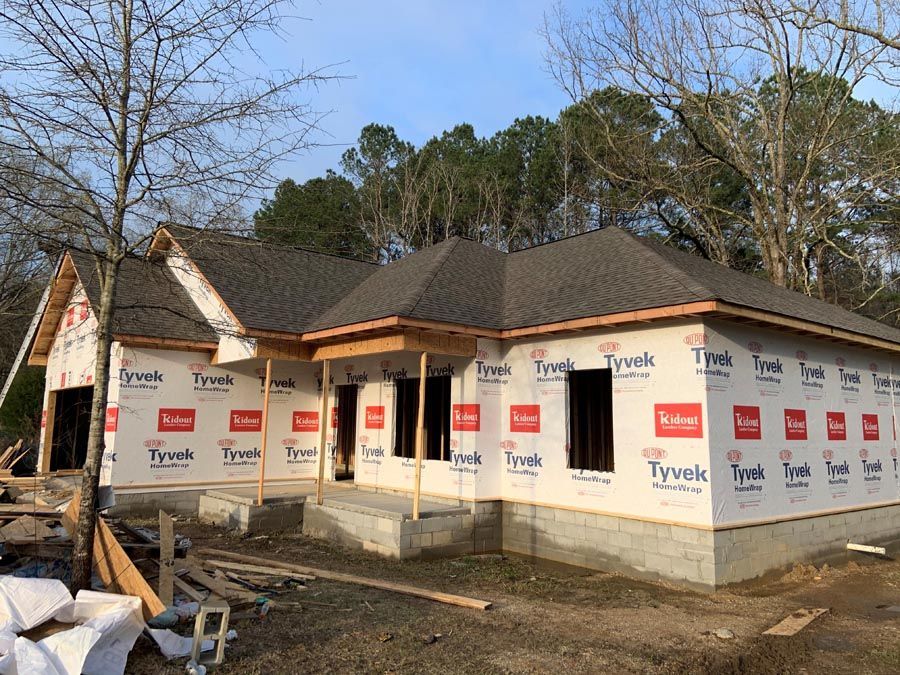 A house is being built in the woods with trees in the background.