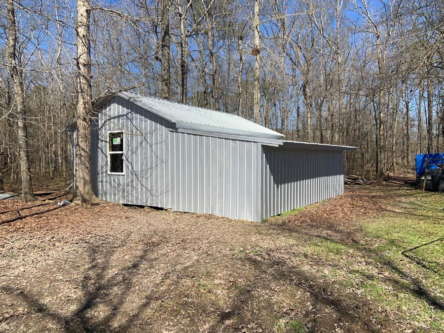 A small metal building is sitting in the middle of a forest.