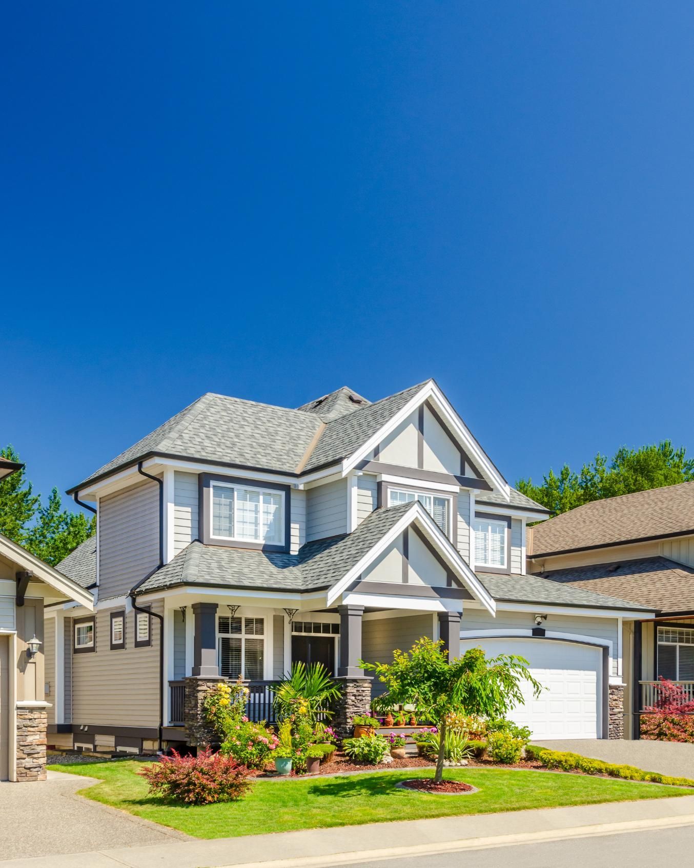 A large house is sitting on top of a lush green lawn in a residential neighborhood.