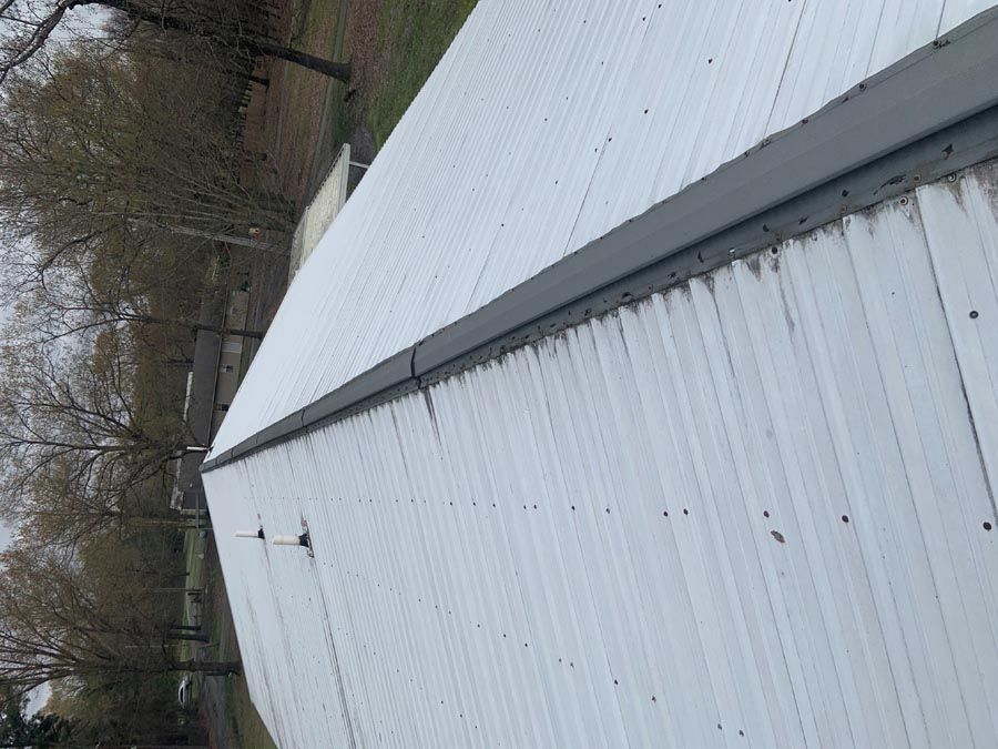 A white building with a black gutter on the side of it.