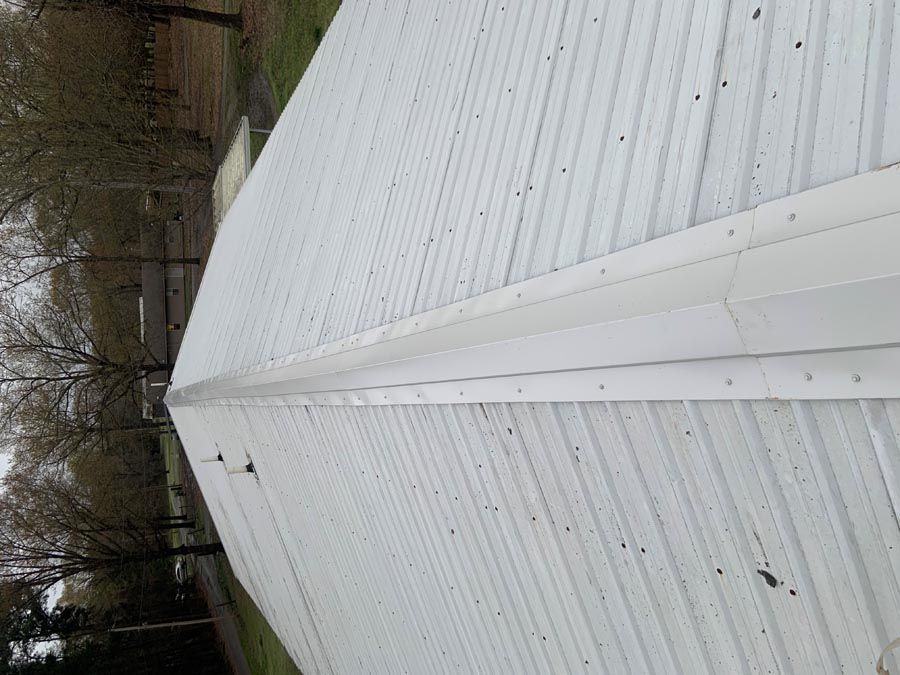A white roof of a building with trees in the background.