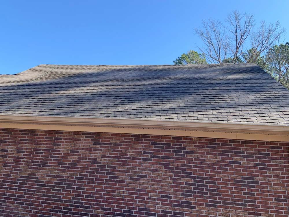 A brick building with a roof and a blue sky in the background.