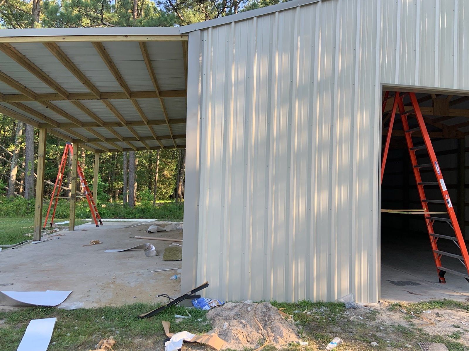 A metal building with a ladder in front of it is being built.