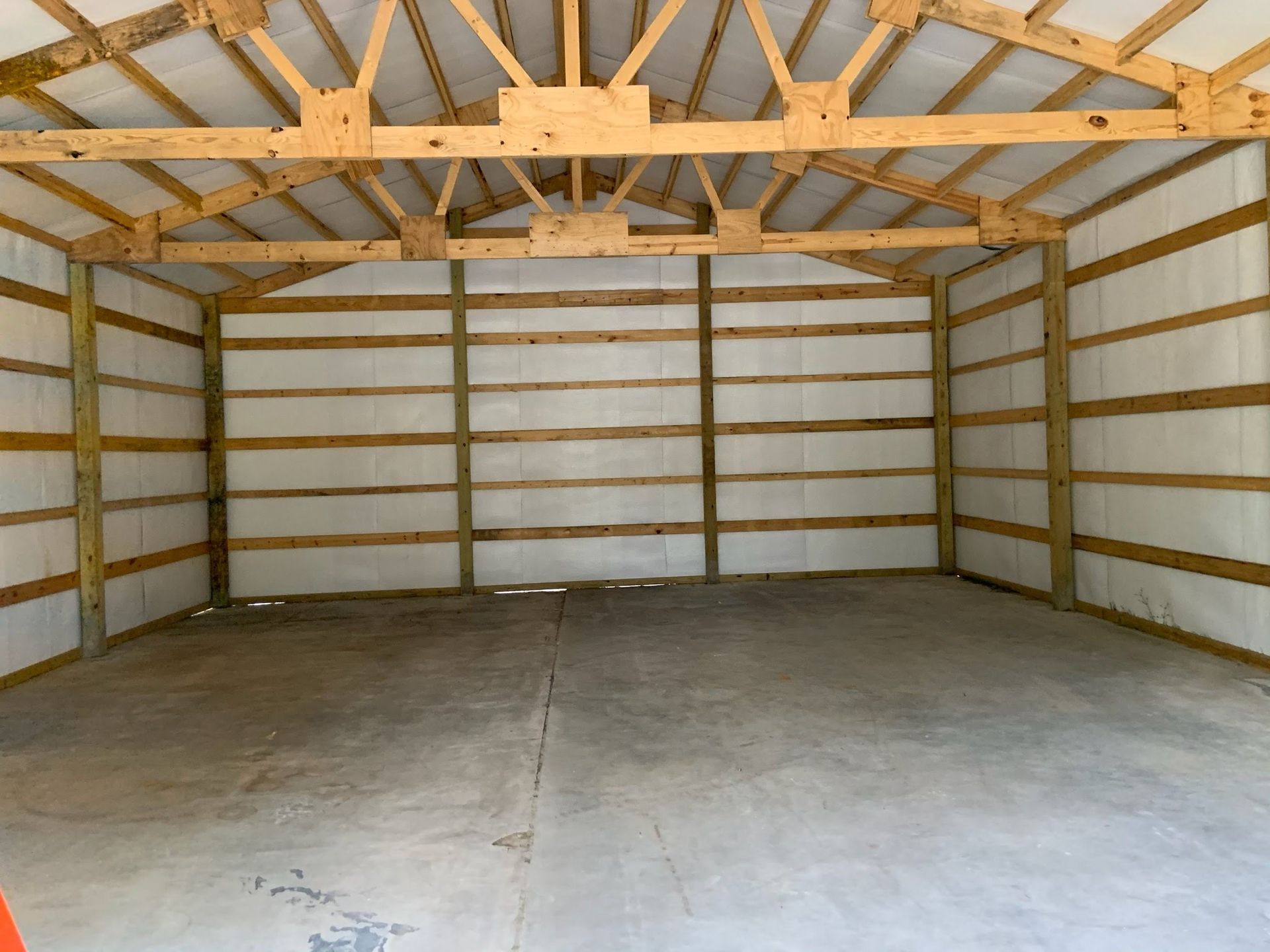 An empty garage with wooden beams and a concrete floor.
