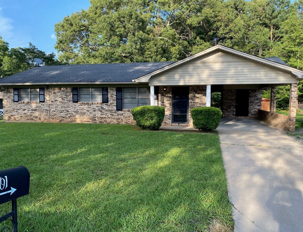 A brick house with a black roof and a mailbox in front of it.