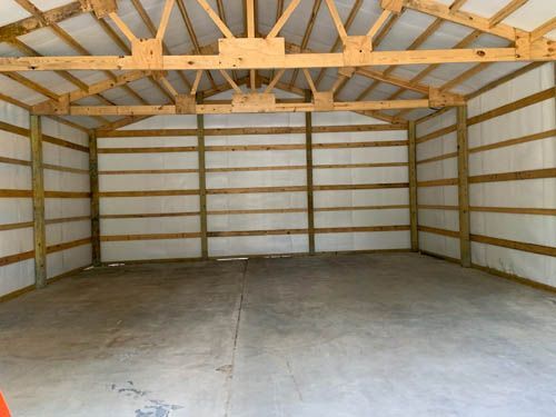 A large empty garage with wooden beams and a concrete floor.