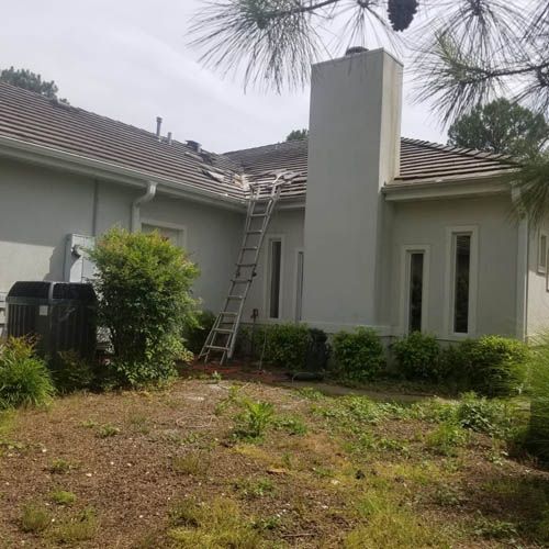 A white house with a ladder on the side of it.