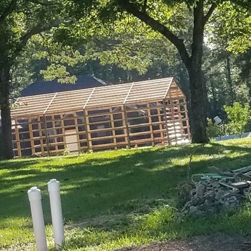 A wooden structure is being built in the middle of a lush green field.
