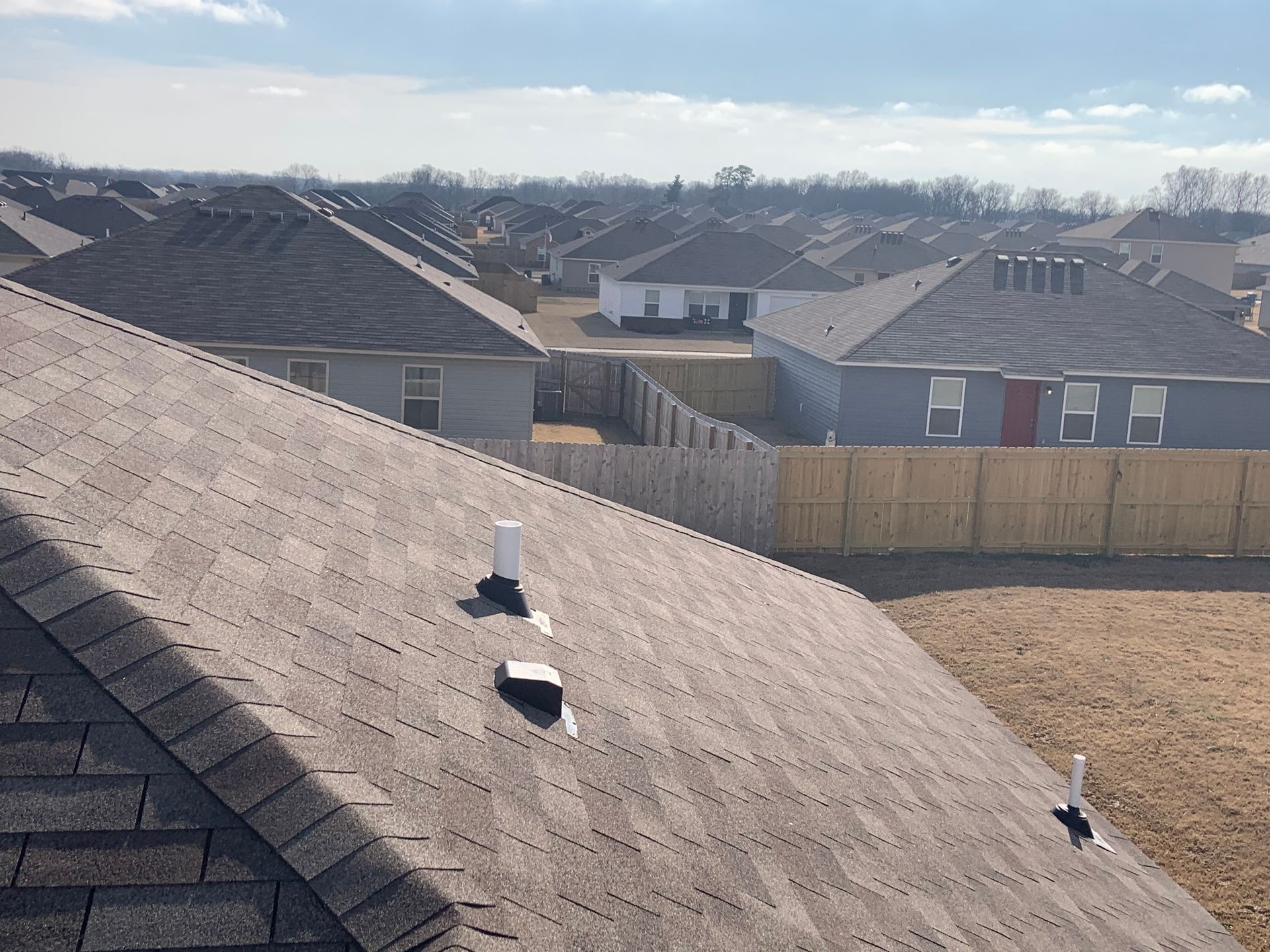 The roof of a house with a wooden fence in the background.