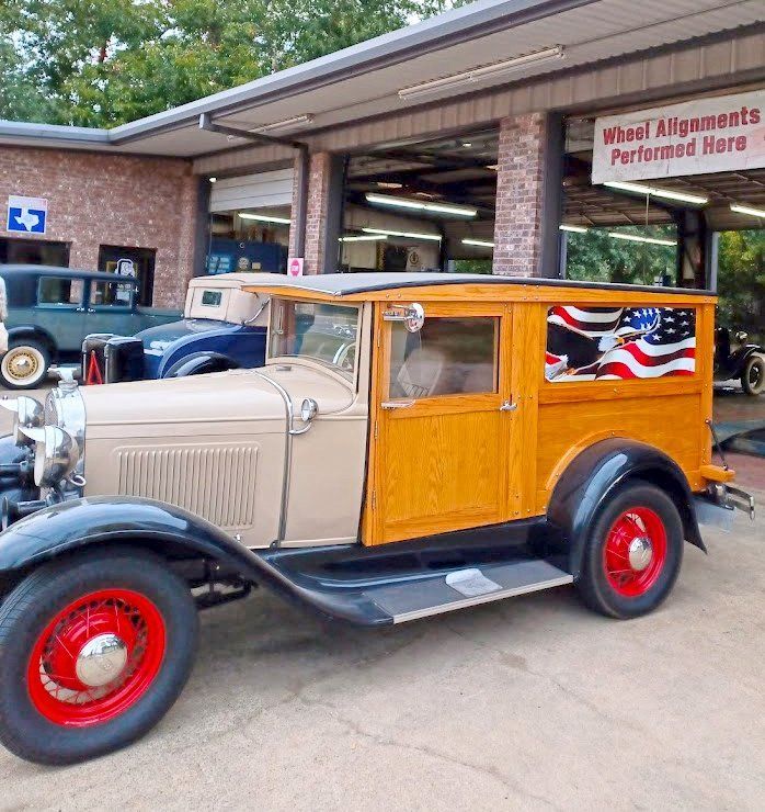An old car is parked in front of a building that says wheel kings