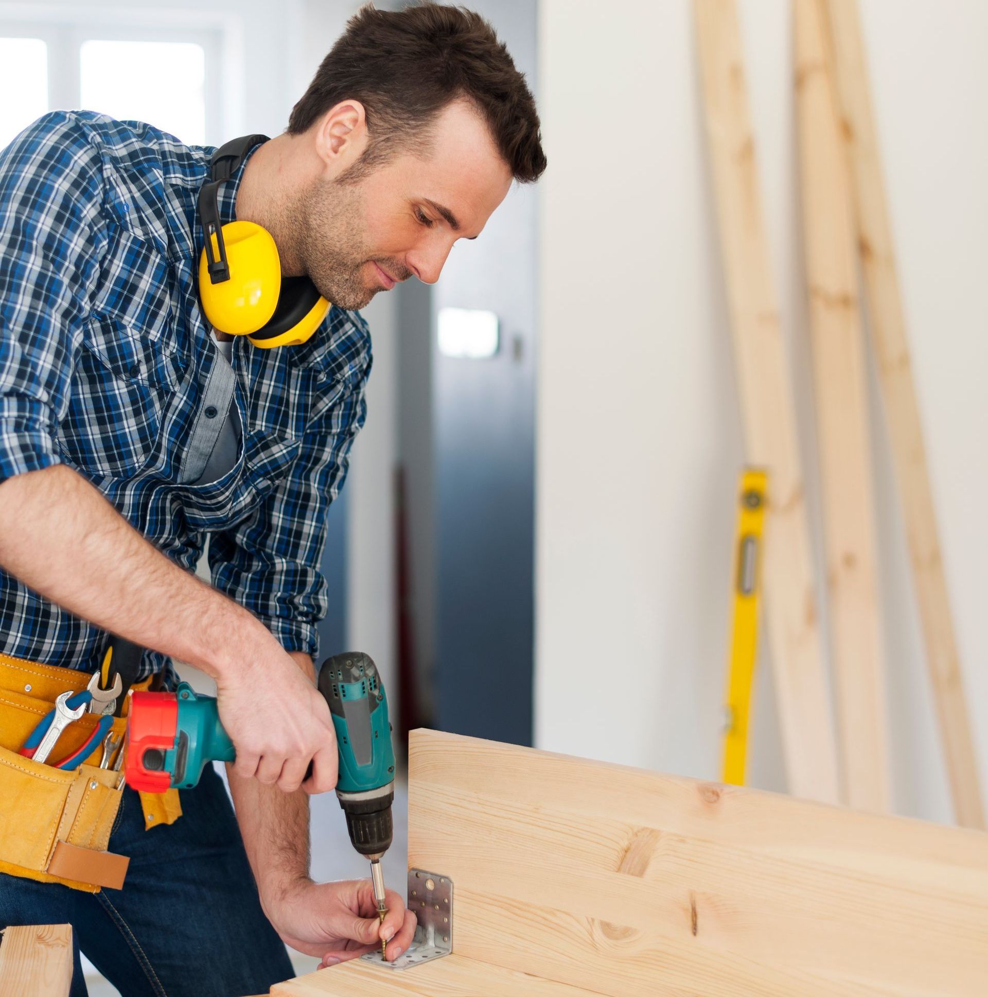 a man wearing headphones is using a drill on a piece of wood
