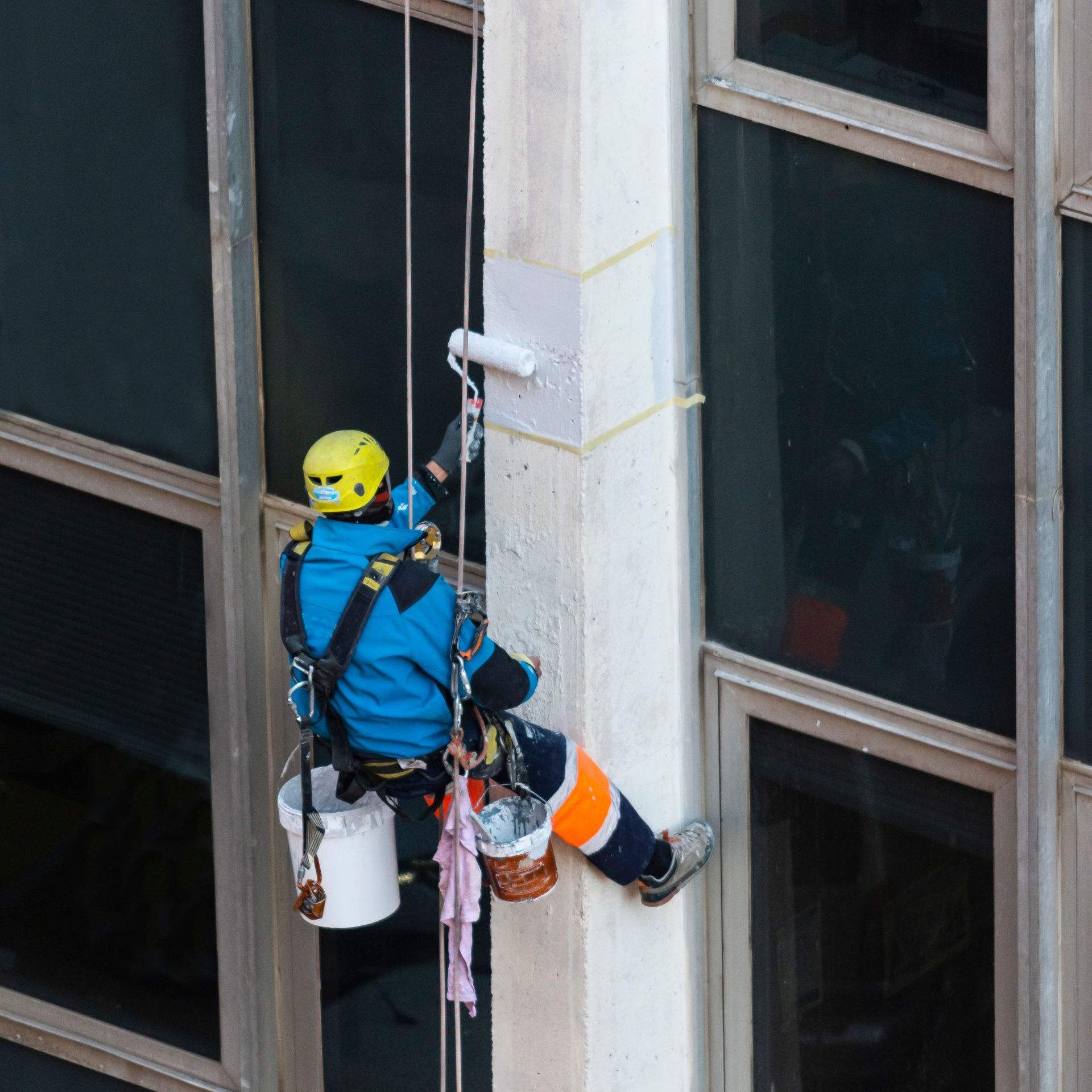 a man wearing a yellow helmet is painting a building