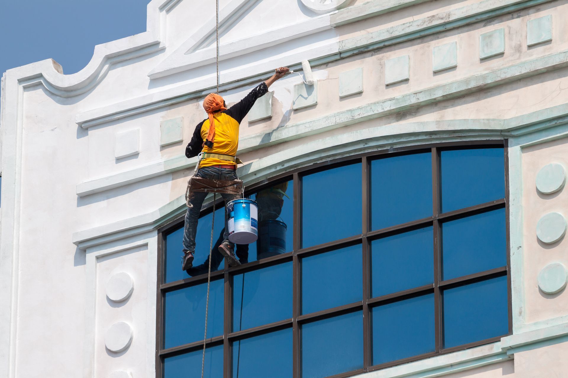 a man is cleaning the windows of a tall building .