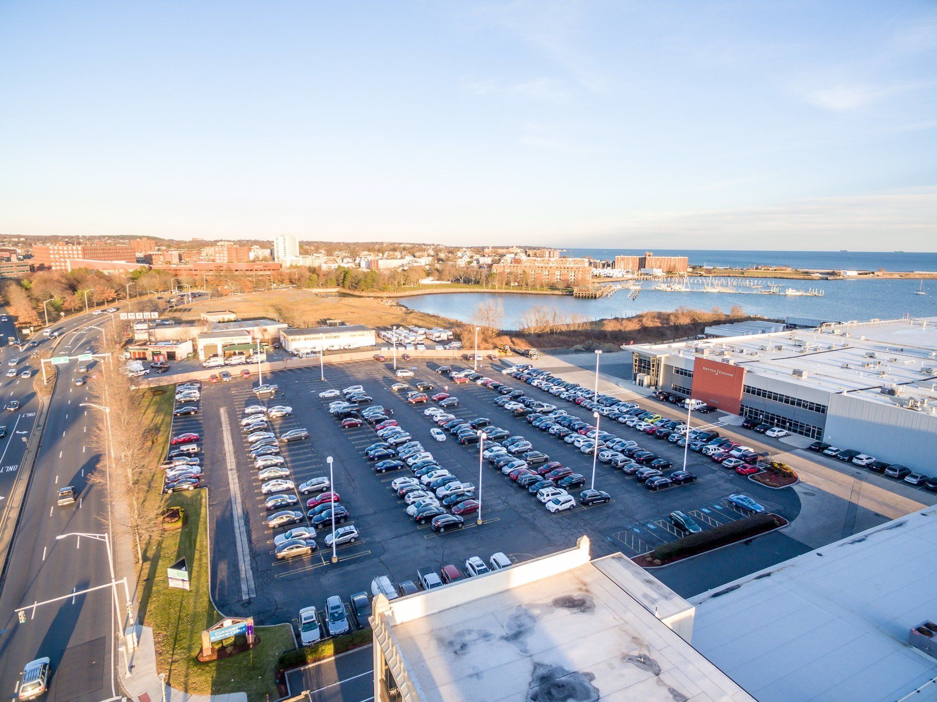 An aerial view of a parking lot filled with cars next to a body of water.