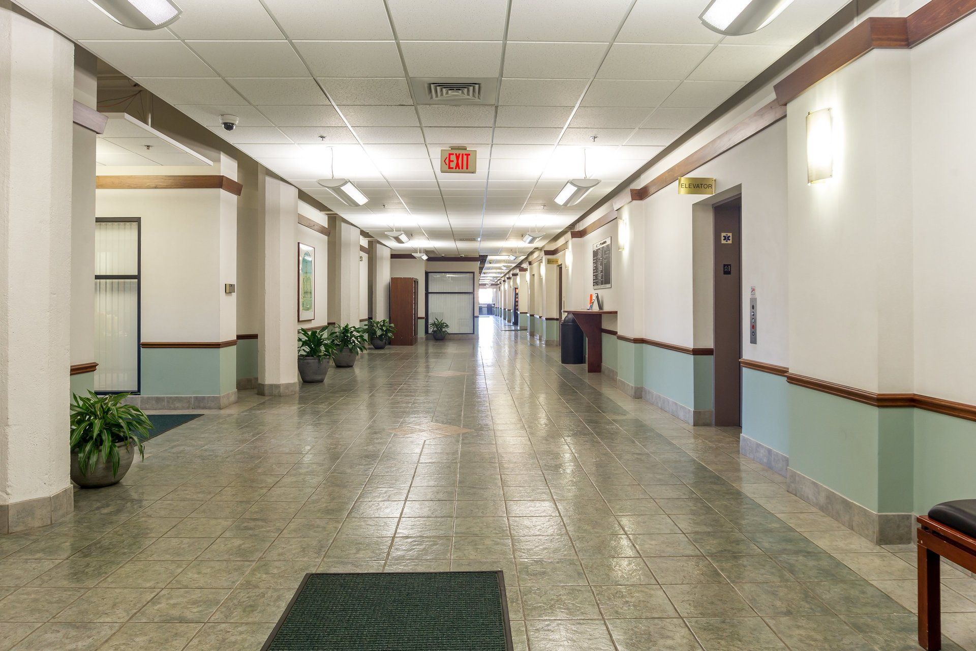 A long hallway in a building with a green rug on the floor.