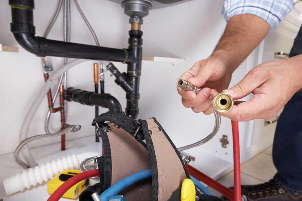Hands Wrapping Thread Around a Small, Dark Object — FNQ Footprints Plumbing In Whitfield, QLD