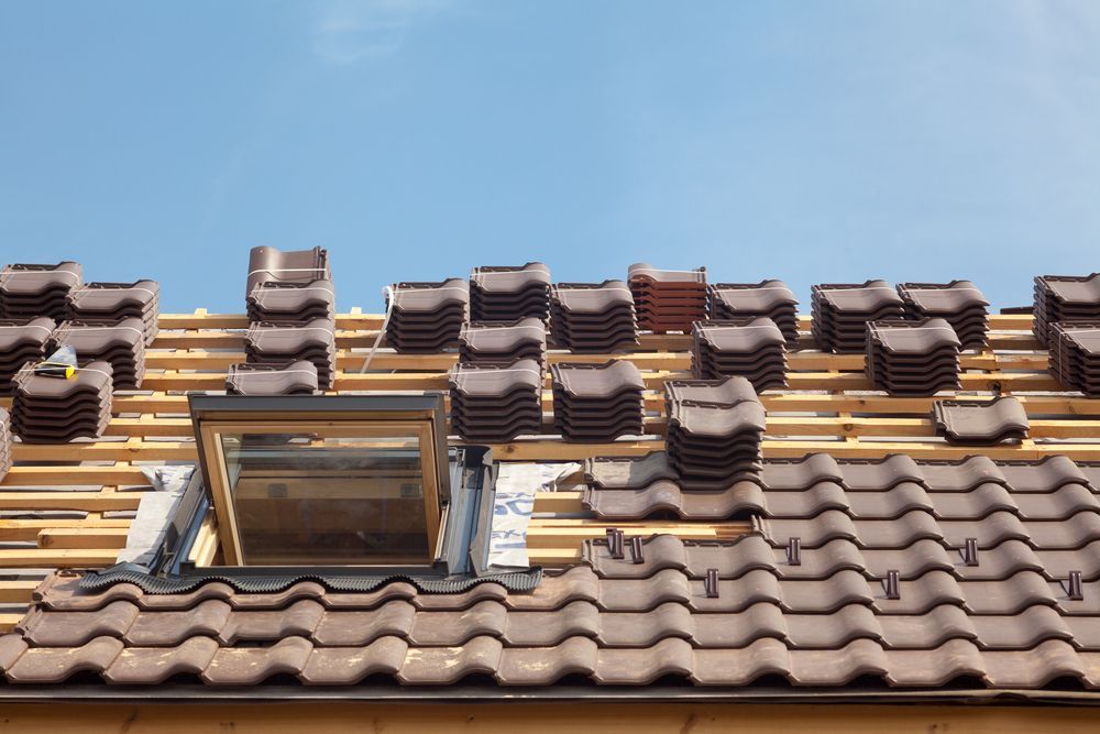 Roof with Brown Tiles in The Process of Being Installed, Skylight, Wooden Beams, Blue Sky — FNQ Footprints Plumbing In Whitfield, QLD