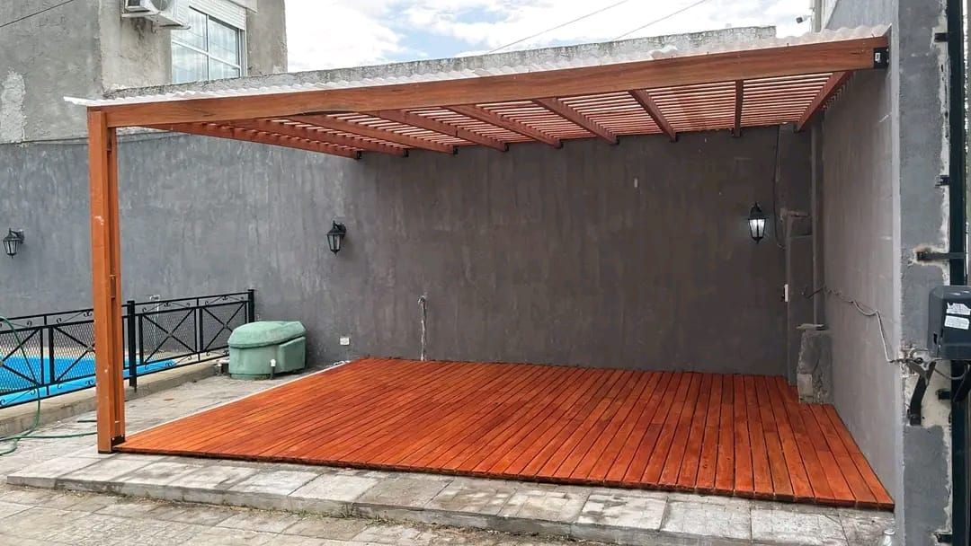 Cubierta de patio de madera con piso de madera contra paredes grises.