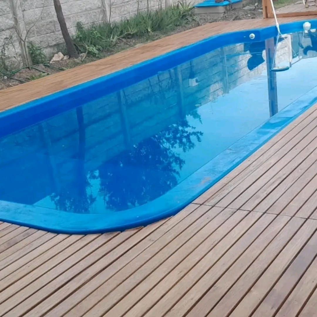 Piscina rectangular de color azul rodeada de tarima de madera.