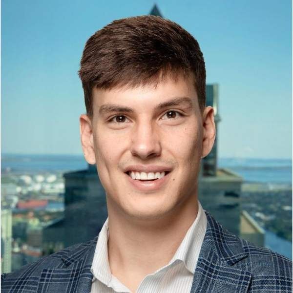 A young man in a suit and white shirt is smiling for the camera.