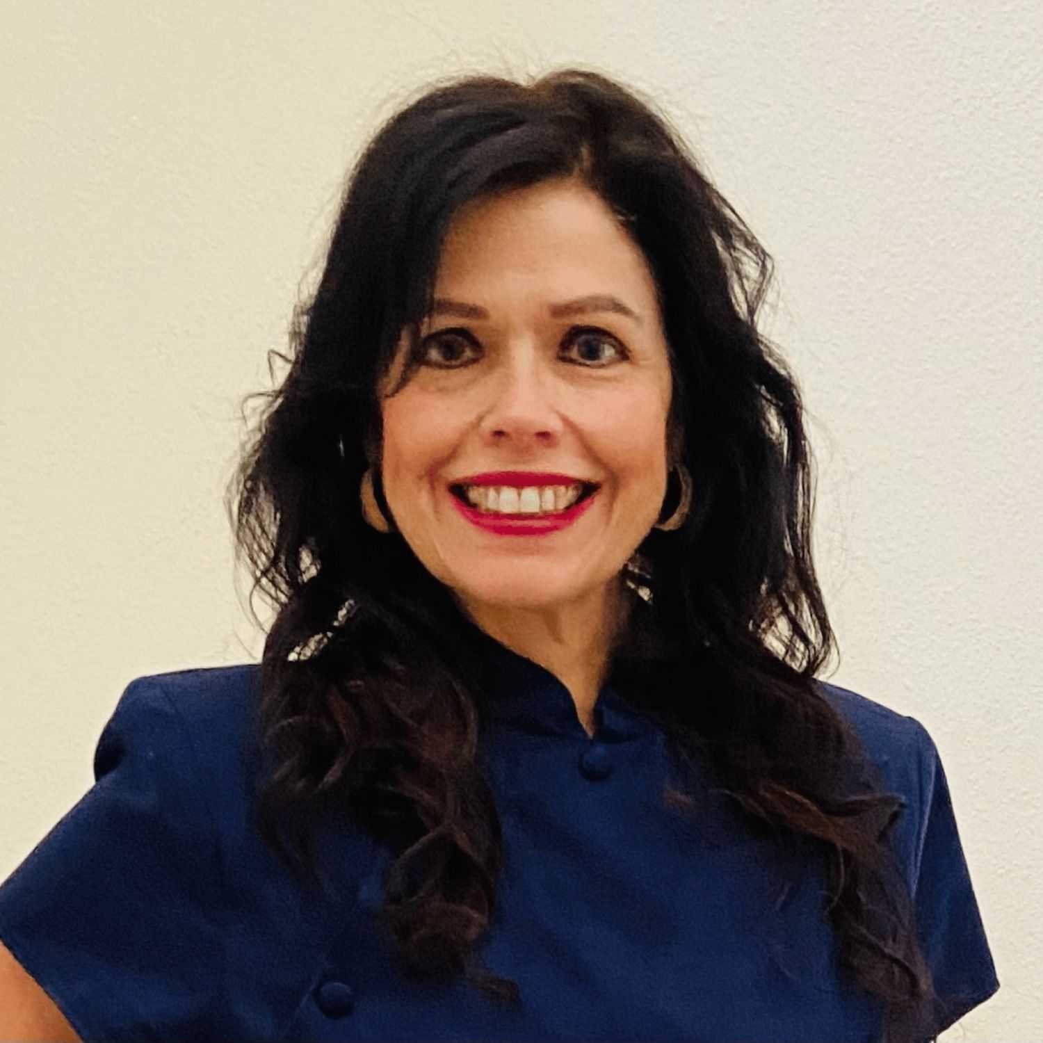A woman wearing a blue shirt and red lipstick is smiling for the camera.