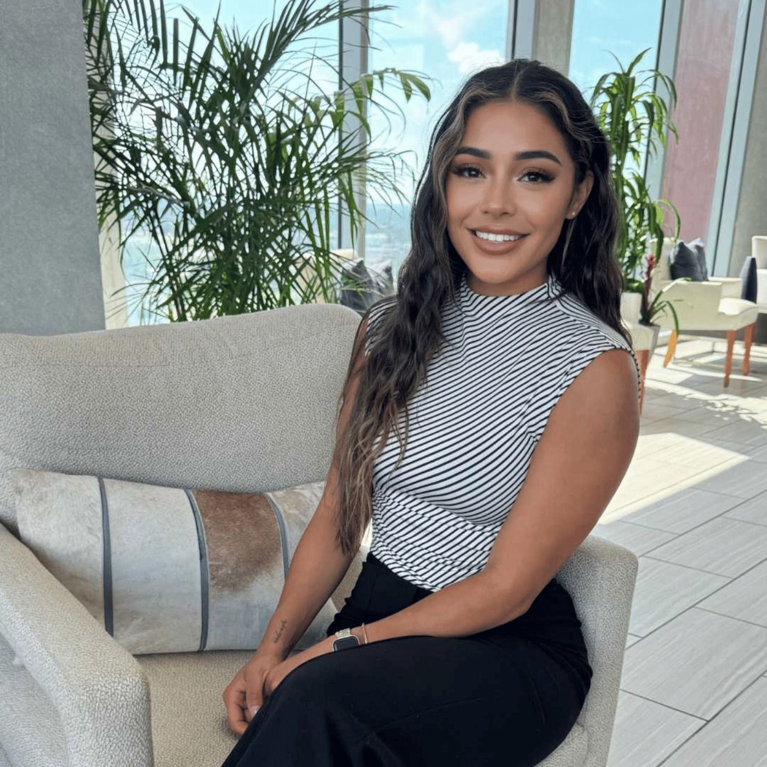 A woman is sitting in a chair and smiling for the camera.