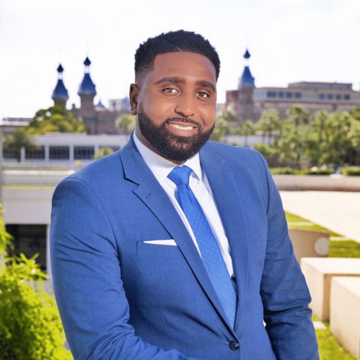 A man with a beard is wearing a blue suit and tie.