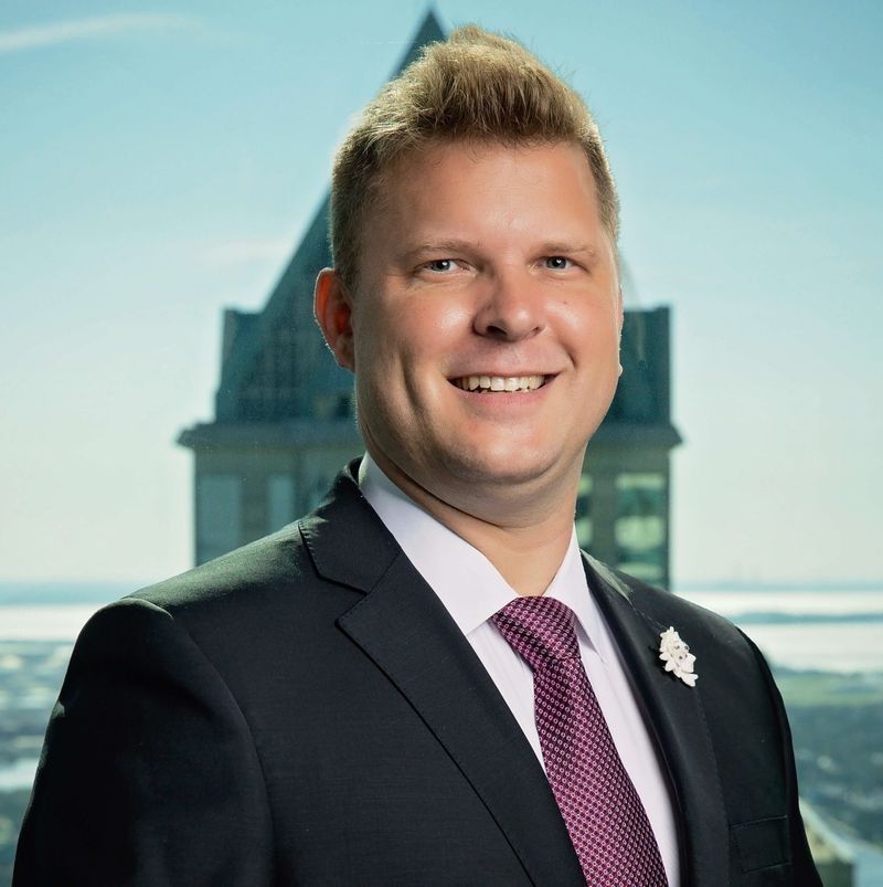 A man in a suit and tie is smiling in front of a building.