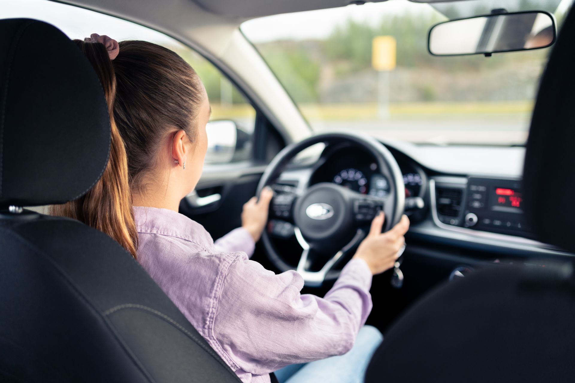 A woman is sitting in the driver 's seat of a car.