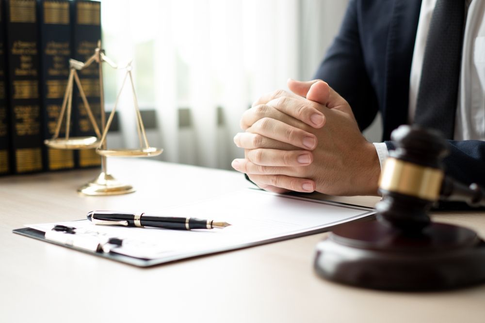 A lawyer is sitting at a desk with his hands folded.