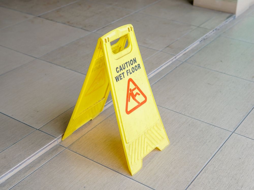 A yellow caution wet floor sign on a tiled floor