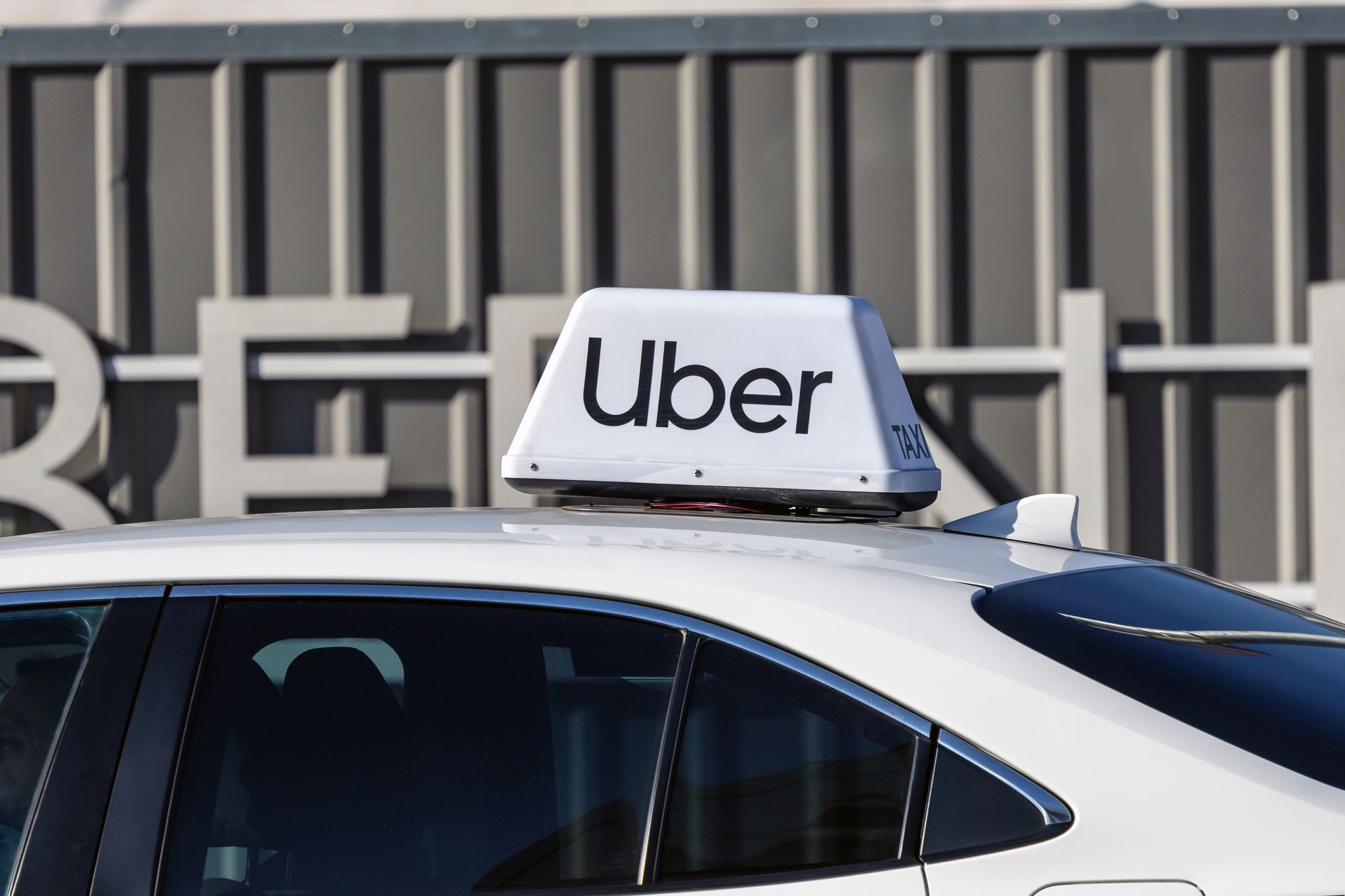 White Uber car with rooftop sign, parked outdoors.