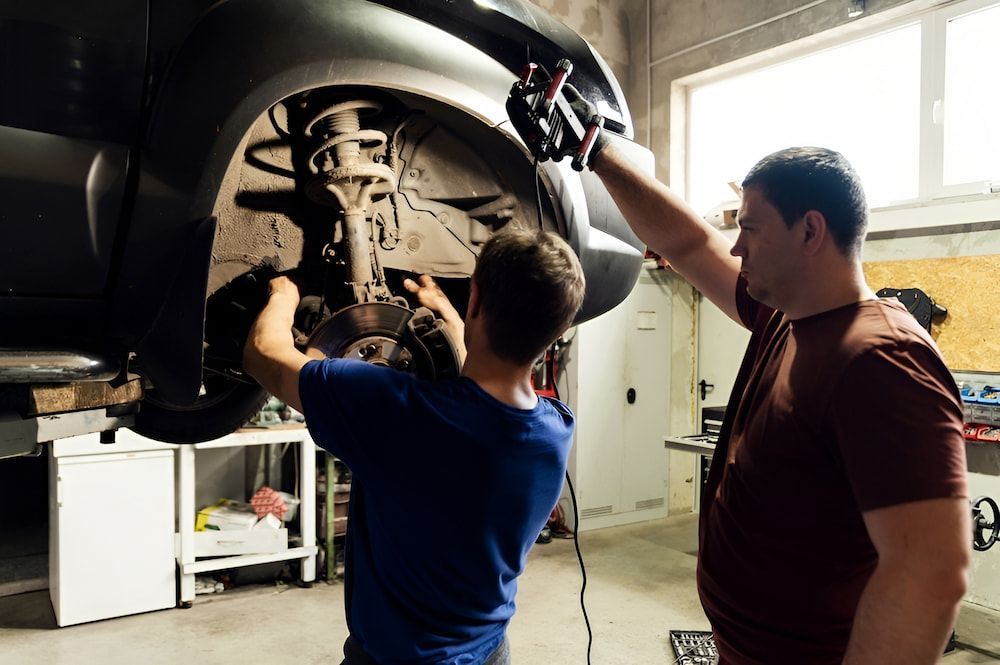 Two Men Are Working On A Car In A Garage — Figtree Brake & Clutch Services in Fairy Meadow, NSW