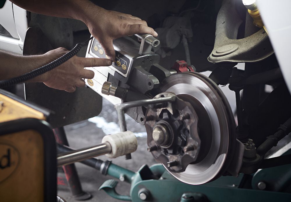 A Man Is Working On A Brake Disc On A Car — Figtree Brake & Clutch Services in Balgownie, NSW