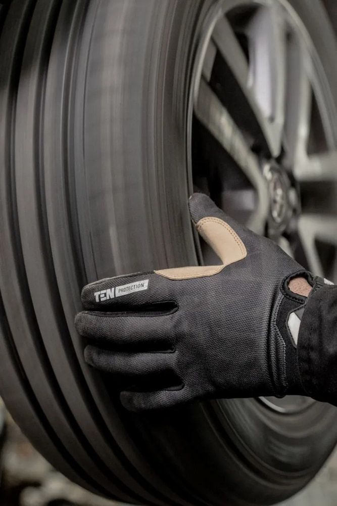 A Person Wearing Gloves Is Holding A Tire In Their Hand — Figtree Brake & Clutch Services in Figtree, NSW