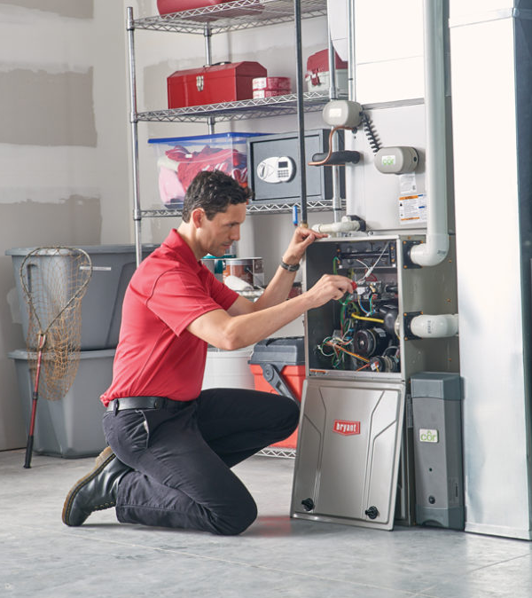 A man in a red shirt is working on a furnace
