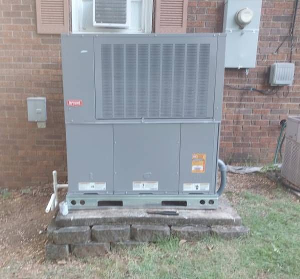 A large air conditioner is sitting on the side of a brick building.