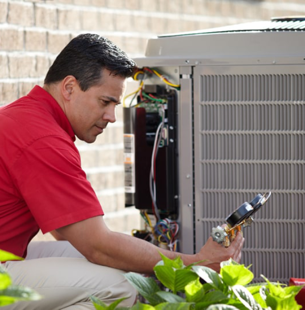A man in a red shirt is working on an air conditioner